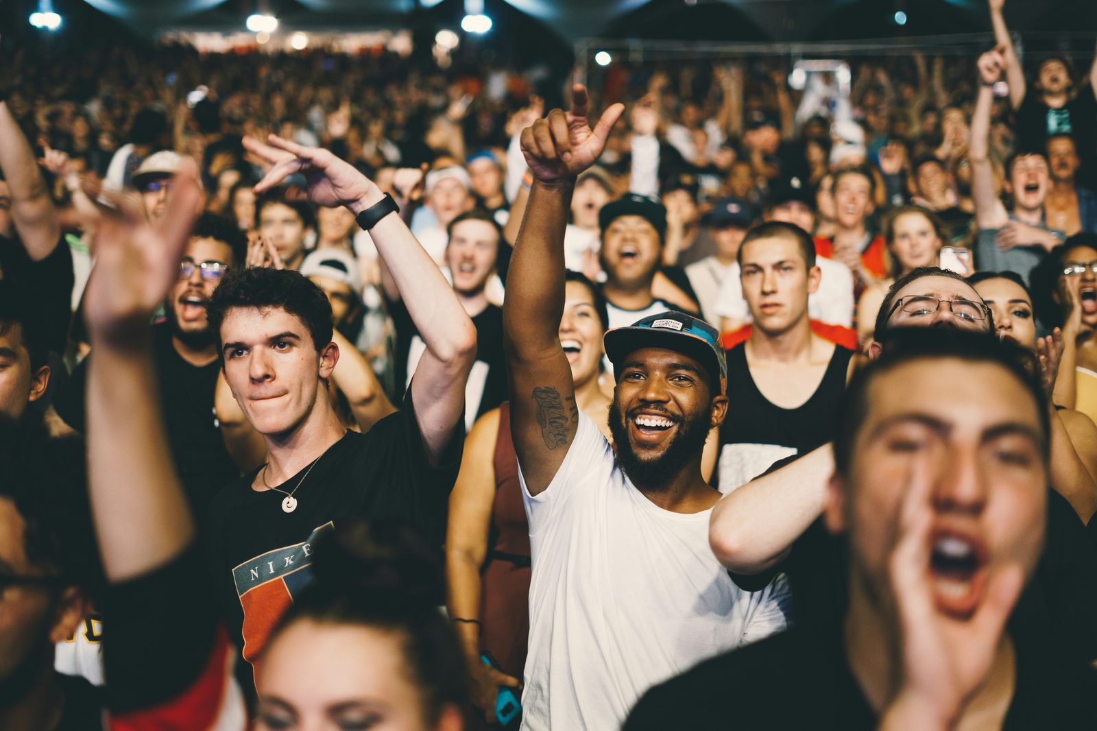 A large crowd cheering with hands raised