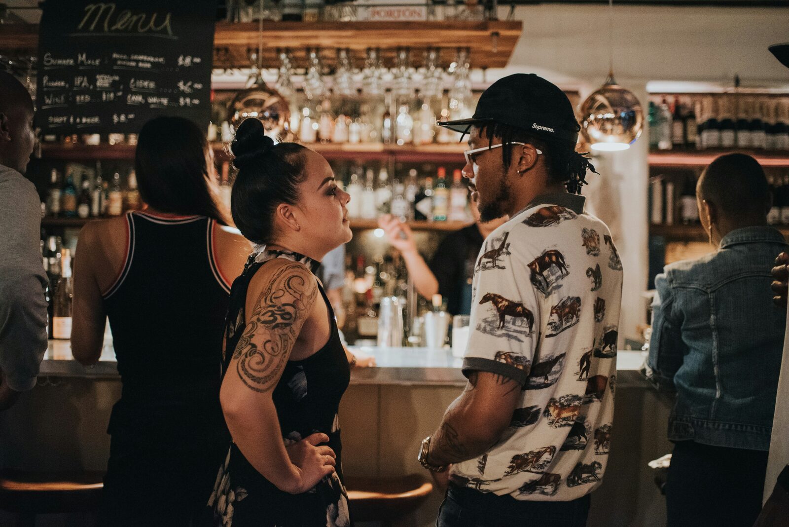 A couple talking at a bar in a relaxed evening setting.